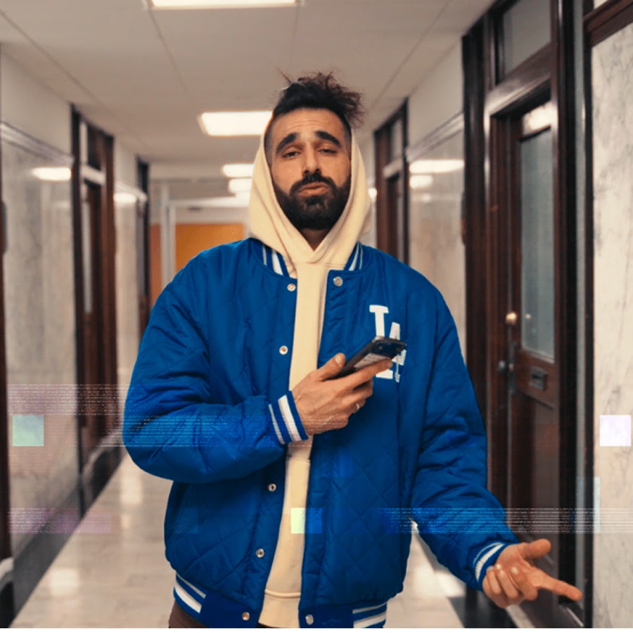 Dousiiee wearing a blue LA jacket and cream hoodie